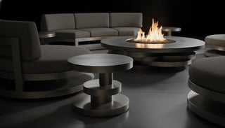 Modern outdoor seating area with a fire pit table and chairs in a dark setting.